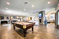 Luxurious common area with a classic pool table, modern seating, and a cozy stone fireplace, perfect for leisure and entertainment.