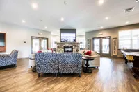 Inviting modern living area featuring stylish patterned armchairs, a cozy stone fireplace, and elegant wood flooring, perfect for relaxation and entertaining.