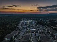 Stunning aerial view of modern apartment complex nestled amid lush greenery at sunset, highlighting a serene and vibrant community setting.