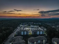 Enchanting evening aerial view of a serene apartment complex nestled in lush greenery, highlighted by a breathtaking sunset sky.