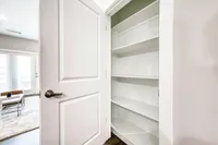 Bright and inviting open door revealing a spacious closet with built-in shelving, perfect for versatile storage solutions in a modern apartment.