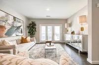 Bright and elegant living room with modern decor, featuring a plush sofa, chic artwork, and large windows allowing ample natural light.