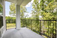 Charming balcony offering a serene view of lush green trees, perfect for relaxation and enjoying nature.