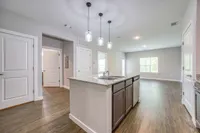 Bright and modern open-concept kitchen and living space with sleek granite countertops and elegant pendant lighting.