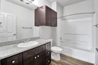 Elegant bathroom with modern fixtures, dark wood cabinetry, granite countertops, and a spacious bathtub.