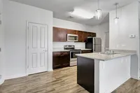 Modern kitchen with sleek granite countertops, stainless steel appliances, rich wood cabinetry, and elegant lighting, perfect for culinary creativity.