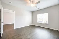 Bright and airy bedroom with hardwood floors, modern ceiling fan, and large window for natural light.