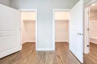 Bright and modern apartment closet space with sleek wooden flooring, ample light, and elegant white doors.