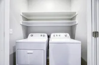 Bright and modern laundry room with high-efficiency washer and dryer, complemented by sleek shelving for storage solutions.