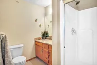 Inviting bathroom featuring a warm wooden vanity, elegant wall accents, and a sleek shower area, perfect for relaxation.