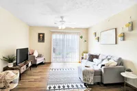 Bright and inviting living room with modern decor, featuring a cozy gray sofa, stylish wall art, and large sliding glass doors that let in natural light.
