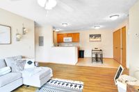 Inviting open-concept living room with cozy sectional sofa, stylish decor, and a modern kitchen featuring warm wooden cabinets.