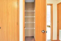 Inviting walk-in closet with wooden doors and ample shelving, ideal for organized storage in a cozy apartment.