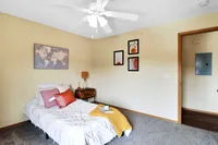 Cozy bedroom with stylish decor, featuring a plush bed with vibrant cushions, modern artwork, and a warm, inviting atmosphere.