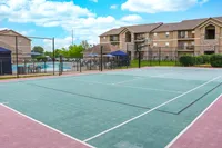 Inviting apartment complex with a vibrant outdoor tennis court and refreshing pool area, perfect for active living and relaxation.
