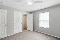 Bright, inviting bedroom featuring soft carpet, natural light from a large window, and a spacious closet with double doors.
