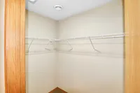Spacious walk-in closet with ample shelving and natural wood accents, perfect for organized storage.