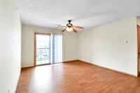 Bright living room with elegant wooden flooring and large sliding glass doors leading to a sunny balcony.