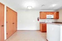 Bright and inviting kitchen space featuring sleek wooden cabinets, a modern microwave, and elegant tiled flooring.