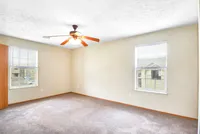 Bright, spacious empty room with large windows and modern ceiling fan, perfect for customization and natural light.