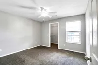 Bright and airy bedroom with plush carpet, ceiling fan, and a walk-in closet, perfect for creating a serene retreat.