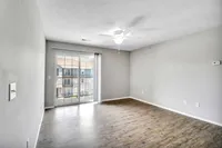 Bright and airy living room with elegant wooden flooring, large window doors leading to a scenic balcony view.