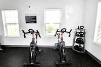 Inviting fitness center with state-of-the-art exercise bikes and kettlebells, bathed in natural light from large windows.