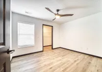Bright bedroom with sleek wooden flooring, modern ceiling fan, and a walk-in closet.
