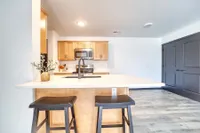 Bright and modern kitchen with sleek countertops, stylish wooden cabinets, and inviting bar stools.