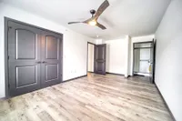 Bright and airy bedroom with elegant double doors, modern ceiling fan, and sleek wooden flooring.