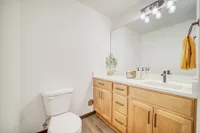 Bright and modern bathroom with elegant wood cabinetry, large mirror, and chic lighting, creating a welcoming and refreshing space.