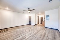 Spacious open-plan apartment featuring modern wood flooring, a ceiling fan, and bright interiors with access to multiple rooms, ideal for stylish living.