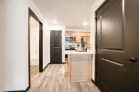 Modern apartment kitchen with sleek cabinetry, stainless steel appliances, and warm wood flooring.