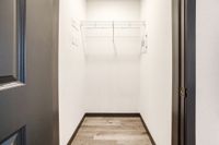 Bright and spacious walk-in closet with modern laminate flooring and sleek shelving, perfect for efficient storage.