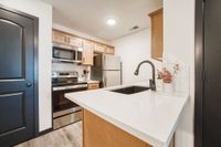 Contemporary kitchen with sleek stainless steel appliances, elegant cabinetry, and a pristine quartz countertop featuring a stylish black faucet.