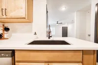 Modern kitchen with sleek black sink, elegant wood cabinets, and a chic open layout leading into a bright living space.
