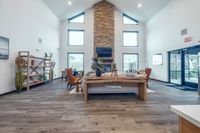 Elegant living room with high ceilings, large windows, and a central stone fireplace. Features stylish furnishings and natural light.