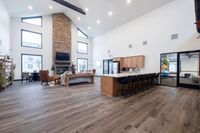 Spacious and modern open-concept living area with high ceilings, stone fireplace, elegant kitchen, and stylish decor.