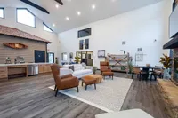 Spacious, modern living area with vaulted ceilings, featuring cozy seating, a rustic kitchen, and elegant decor.