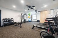 Modern fitness room equipped with treadmills, weight bench, and vibrant stability balls, offering a well-lit and inviting workout environment.