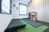 Tranquil yoga room with plush mats, cozy seating, and stylish wooden shelving creating a serene ambiance.