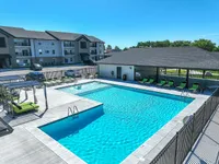Inviting apartment complex with a sparkling swimming pool, surrounded by cozy lounge chairs and a spacious deck, perfect for relaxation and leisure.