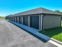 Modern storage units with sleek doors in a well-maintained facility surrounded by lush green grass.