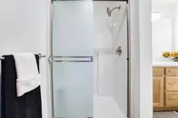 Modern bathroom with a sleek glass shower door, elegant chrome fixtures, and a cozy vanity with natural wood accents.