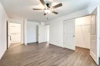 Bright and spacious bedroom with modern hardwood floors, ceiling fan, and generous walk-in closet.