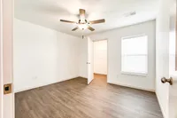 Bright, modern bedroom with elegant hardwood floors, ceiling fan, and a spacious walk-in closet.
