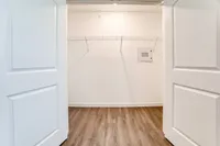 Bright and spacious walk-in closet with sleek wood flooring and ample shelving.