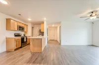 Inviting open-plan kitchen and living room featuring modern wood cabinetry, sleek appliances, and elegant flooring.