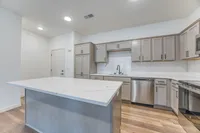 Modern kitchen with sleek gray cabinetry, stainless steel appliances, and a spacious marble island.