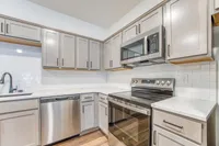Modern kitchen with sleek stainless steel appliances, elegant white subway tile backsplash, and stylish gray cabinetry complemented by marble countertops.